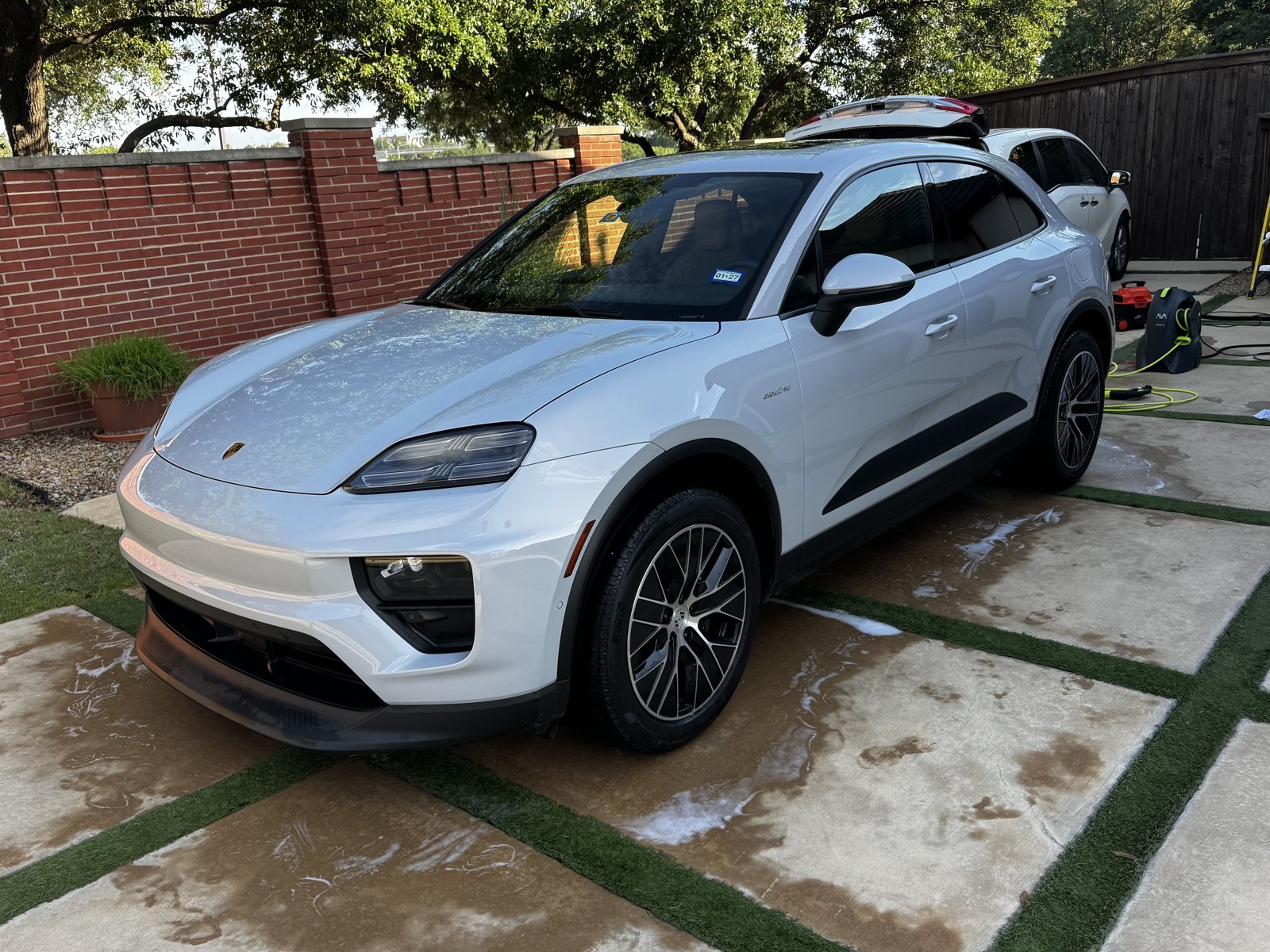 White Porsche Macan Electric after a wash on a paver driveway